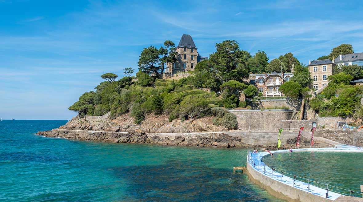 Beach and coastline in Brittany France with buildings on a hill by the water surrounded by trees
